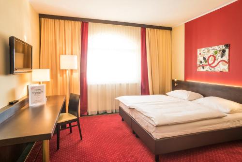 a hotel room with a bed and a desk and a window at Hotel Karl-Wirt in Perchtoldsdorf