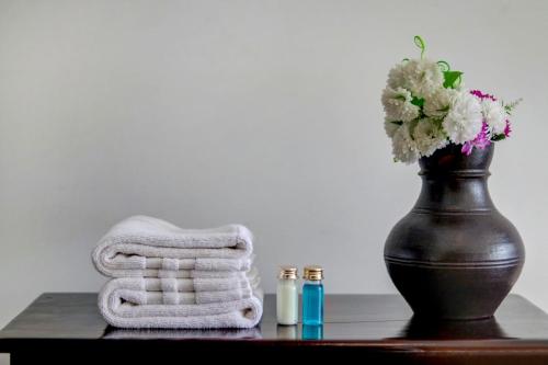 a table with a vase and towels and a vase with flowers at OAK Edassery's Sealine Villa Stay in Cochin