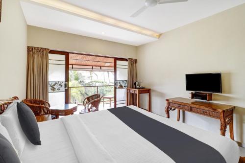 a bedroom with a bed and a desk and a television at OAK Edassery's Sealine Villa Stay in Cochin