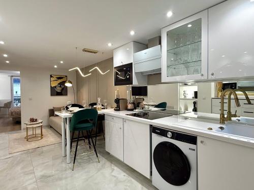 een keuken met witte kasten, een wastafel en een tafel bij Résidence Auguste Comte - avec Balcon - Cœur de Dijon in Dijon