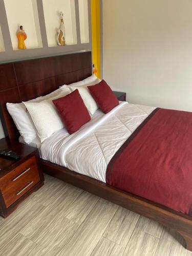 a bedroom with a bed with red and white pillows at Hosteria Mana in El Pangui