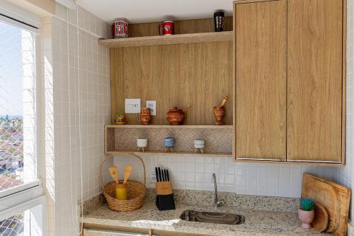 a kitchen with a sink and wooden cabinets at 250m do Mar | Piscina e Roupas de Cama in Bertioga
