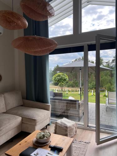 a living room with a couch and a table at Casa Kashubia - Nowoczesny dom wakacyjny nad jeziorem - Cisza natura i komfort in Brzeźno Szlacheckie