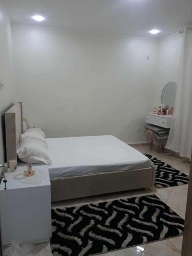 a white bedroom with a bed and a mirror at appartement T2 in Fort de lʼEau