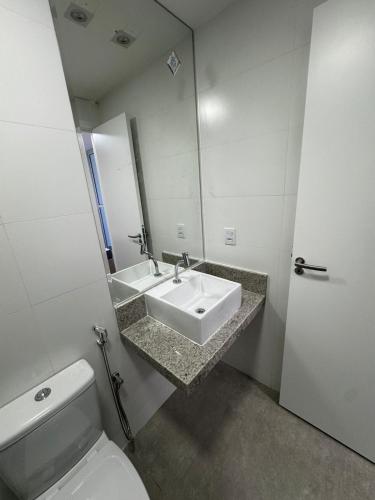 a bathroom with a sink and a toilet and a mirror at Peracanga Bacutia Guarapari LS05 in Guarapari