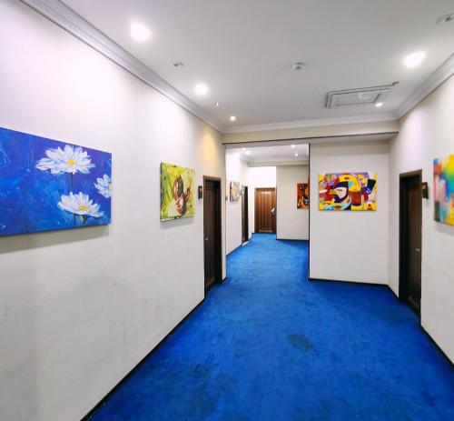 a hallway with a blue carpet and paintings on the walls at TWINS MIRROR group HOTELS in Baku