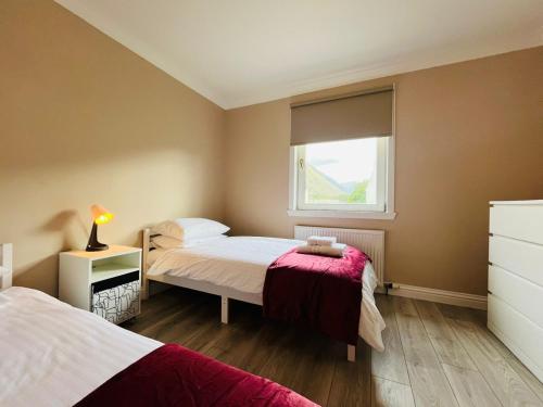 a small bedroom with two beds and a window at Coll’s Dachaigh in Inverlochy