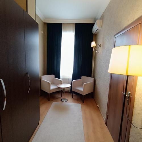 a room with two chairs and a table and a lamp at TWINS MIRROR group HOTELS in Baku