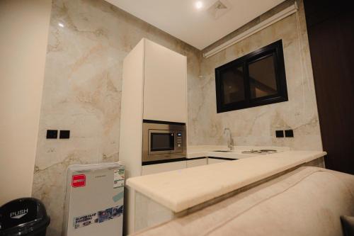a small kitchen with a microwave and a sink at الواجهة in Buraydah