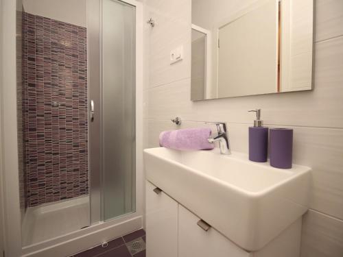 a white bathroom with a sink and a shower at Apartment Kristijan in Šilo