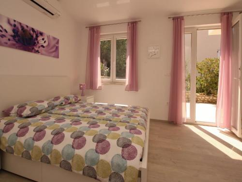 a bedroom with a bed and windows with pink curtains at Apartment Kristijan in Šilo