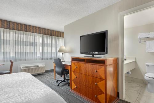 a hotel room with a bed and a television on a dresser at Best Western Plus Suites Downtown Calgary in Calgary