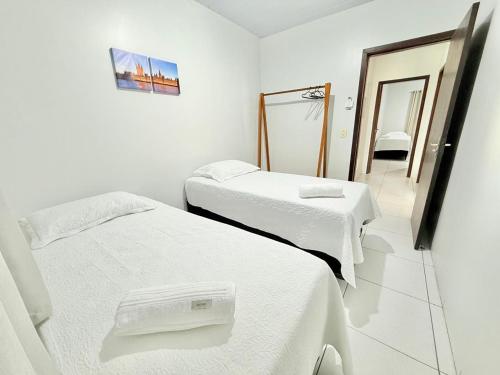 a white room with two beds and a mirror at Ap conforto no centro de Sinop 2 in Sinop