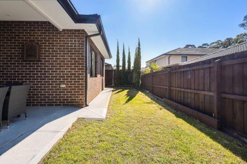 a yard next to a brick building with a fence at Cloverlea Spacious 4BR Yarra Valley Getaway in Lilydale
