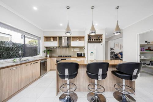 a kitchen with black bar stools and a counter at Cloverlea Spacious 4BR Yarra Valley Getaway in Lilydale