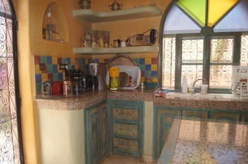 a kitchen with green cabinets and a sink and a window at Villa Nouran - Chambre Hôte in Ghazoua