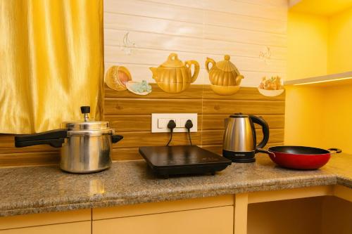 a kitchen counter with a stove with pots and pans at Brand New Spacious and luxurious 2bhk Hill View Apartment in Tirupati close to railway station and bus stand - 201 in Tirupati
