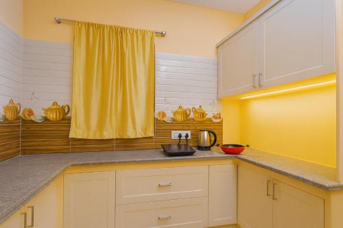 a kitchen with white cabinets and a yellow curtain at Brand New Spacious and luxurious 2bhk Hill View Apartment in Tirupati close to railway station and bus stand - 201 in Tirupati