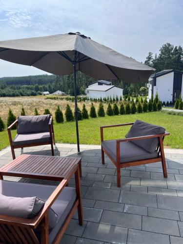 two chairs and an umbrella on a patio at Casa Kashubia - Nowoczesny dom wakacyjny nad jeziorem - Cisza natura i komfort in Brzeźno Szlacheckie