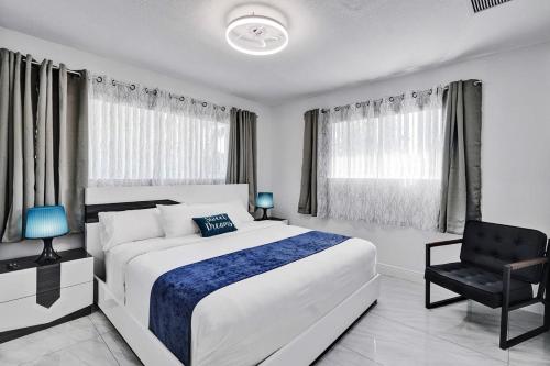 a bedroom with a large white bed and a chair at WALK to Hollywood Beach Stylish 5BR and 4BA Villa in Hollywood Beach