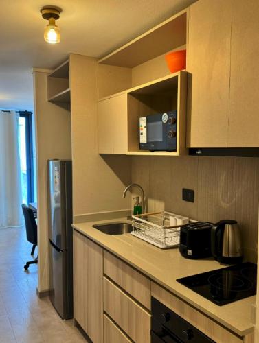 a kitchen with a sink and a refrigerator at Departamento nuevo a pasos del metro irrarazaval in Santiago