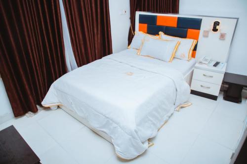 a bedroom with a large white bed with an orange and blue headboard at Le Patriotic Hotel in Aja