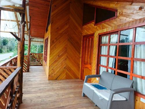 a porch of a wooden cabin with a chair and a window at Cabaña Indi in Santiago