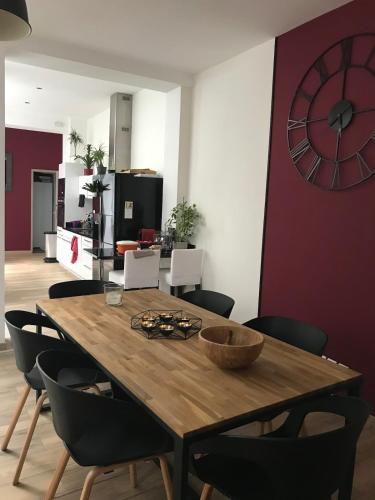 a dining room table with chairs and a clock on the wall at Loft 11 personnes Sauna Jacuzzi in Mouscron