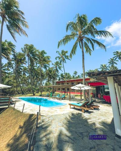 a resort with a swimming pool and palm trees at Igarakuê Flat in Japaratinga