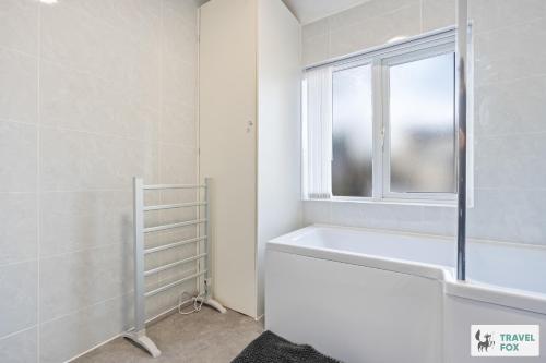 a bathroom with a bath tub and a window at Abbie's House in Nottingham
