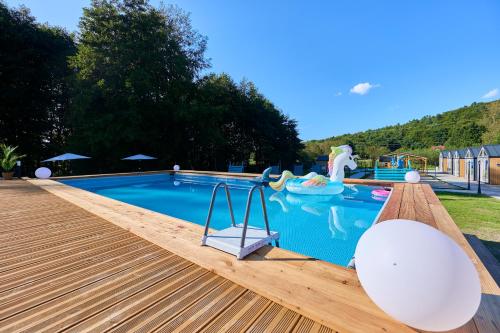 a swimming pool with a wooden deck and a playground at Turkusowa Osada - family resort in Wapnica