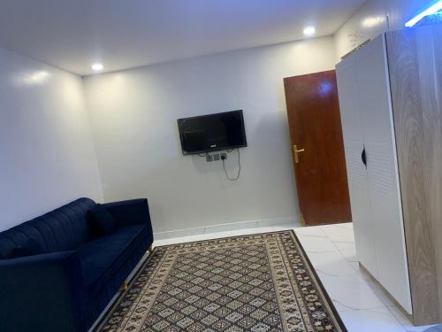 a living room with a couch and a tv on a wall at روضة طيبة السكنية شقة قريبة من الحرم in Al Madinah