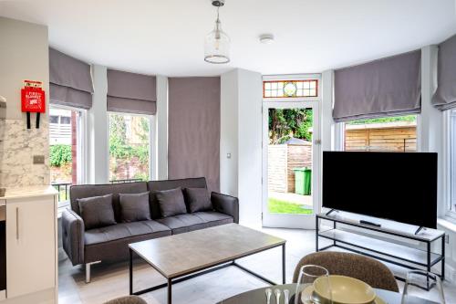 a living room with a couch and a tv at Modern 2 Bed Flat, Wifi, Parking, Self Check-in, Sleeps 5, 2 bathrooms, Close to Stepping Hill & Motorways, Long stays in Stockport