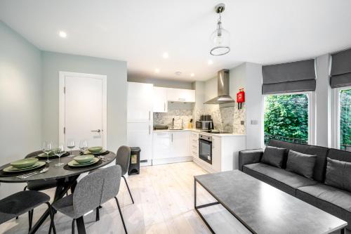 a living room and kitchen with a table and a couch at Modern 2 Bed Flat, Wifi, Parking, Self Check-in, Sleeps 5, 2 bathrooms, Close to Stepping Hill & Motorways, Long stays in Stockport