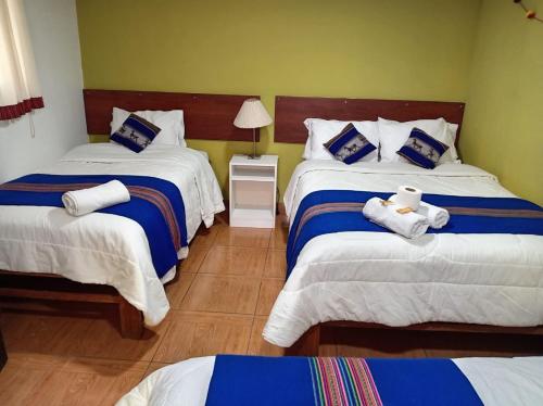 a bedroom with two beds with blue and white sheets at Hosp Sophie in Cusco