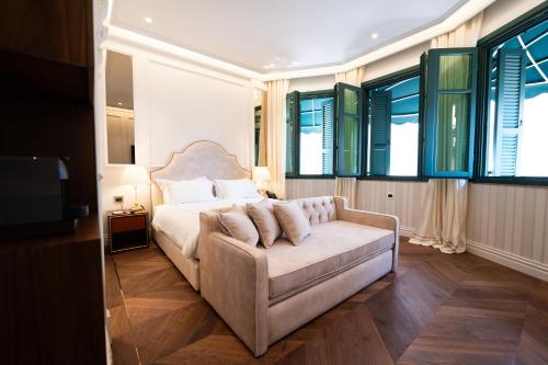 a bedroom with a couch and a bed with windows at La Fe Boutique Hotel Sarande in Sarandë
