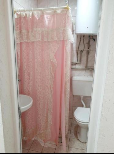 a bathroom with a pink shower curtain and a toilet at Vila Fantastico in Skopje