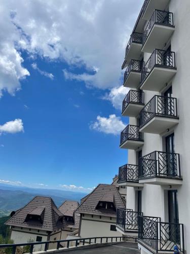 a white building with balconies and a blue sky at NORD VISTA Premium Alpine and SPA Experience in Kopaonik