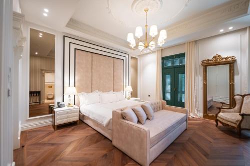 a bedroom with a bed and a couch and a chandelier at La Fe Boutique Hotel Sarande in Sarandë