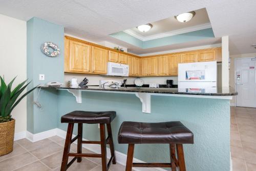 格尔夫海岸Crystal Shores West 807 condo的厨房配有柜台和2张凳子