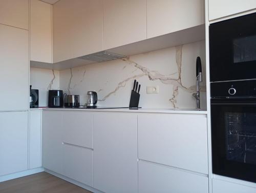 cocina con armarios blancos y microondas negro en Mirante Monte e Mar, en Esposende