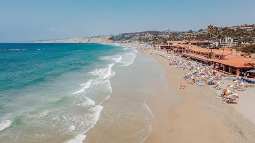 a beach with a bunch of people and the ocean at La Jolla Beach & Tennis Club in San Diego