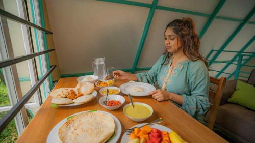 a woman sitting at a table with food at Shenaya Plantation 