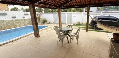 a patio with a table and chairs next to a pool at Casa de Praia Encanto Tamandaré - A 300m das Piscinas Naturais in Tamandaré