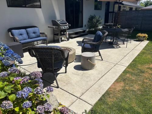 a patio with chairs and a grill and some flowers at Short Walk to DT/ AC/Gas Fire Pit/BBQ/Coffee Bar in Enumclaw
