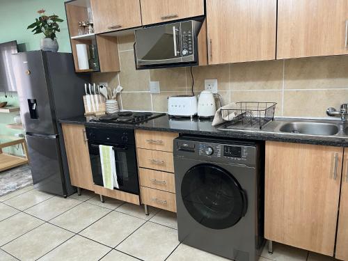 a kitchen with a washing machine and a sink at Luxury Loft eMalahleni in Witbank