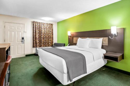 a bedroom with a large bed and a green wall at Americas Best Value Inn - Rome in Lindale