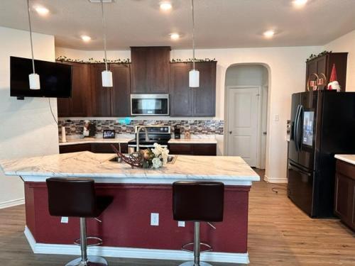 a kitchen with a large island with two bar stools at Perfect Family Getaway sleeps 12 in Seguin