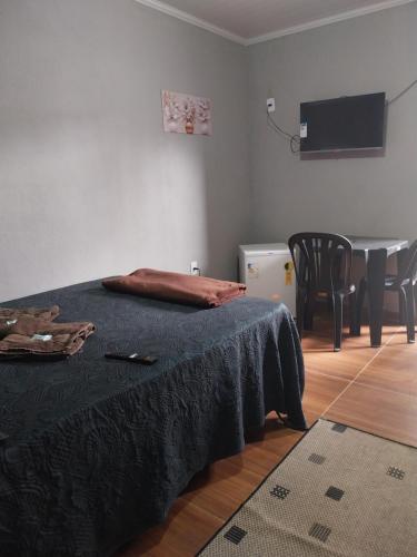 a bedroom with a bed and a table and a television at Suite Jockey 1 in Campos dos Goytacazes