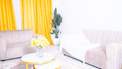 a living room with two couches and a table with flowers at Zuri Stay in Mombasa